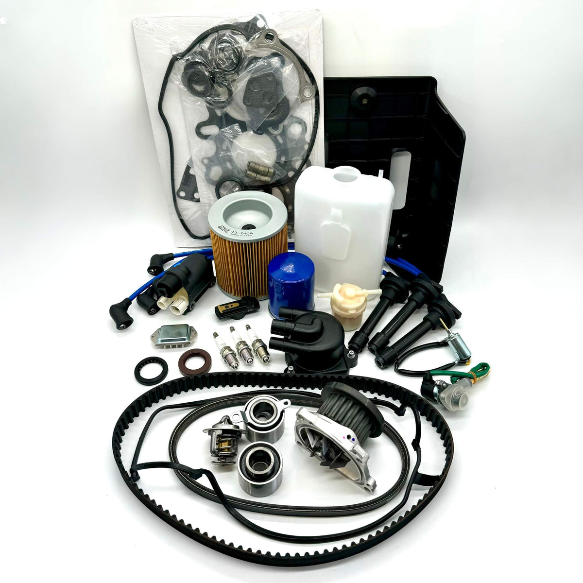 Comprehensive 25-piece Honda Acty HH3/HH4 timing belt and tune-up kit including air, fuel, and oil filters, distributor cap and rotor, spark plugs and wires, ignition control module and coil sensor, ignition assembly, engine gasket set, belts, coolant reserve tank, and battery cover for 1990-1999 models, meticulously packaged for peak performance and free shipping from Oiwa Garage.