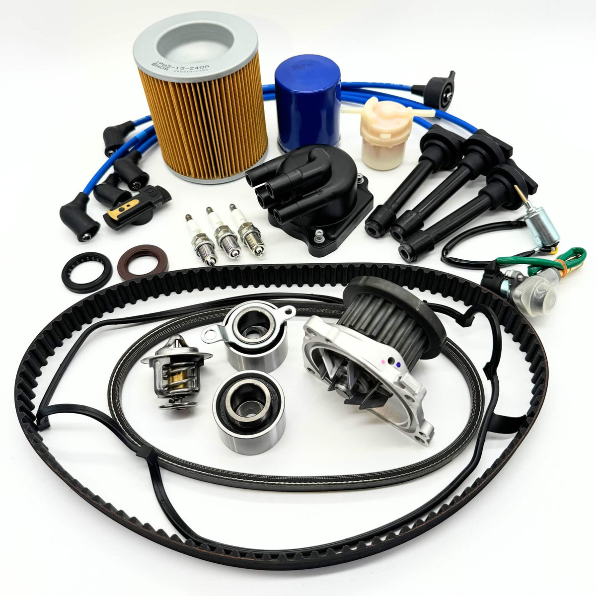 18-piece Mega Timing Belt and Tune-Up Kit for Honda Acty HH3/HH4 1990-1999, including high-quality air filter, fuel filter, oil filter, distributor cap and rotor, spark plugs and wires, premium timing and alternator belts, head cover gasket, and carb solenoids, neatly arranged on a white background with free shipping from Oiwa Garage.